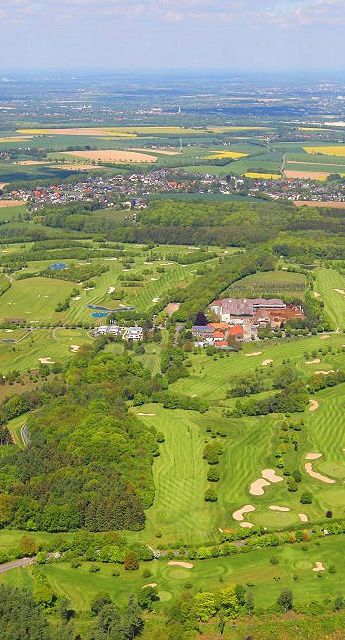 Aerial view of a lush golf course surrounded by vibrant countryside, showcasing manicured greens and natural landscapes.