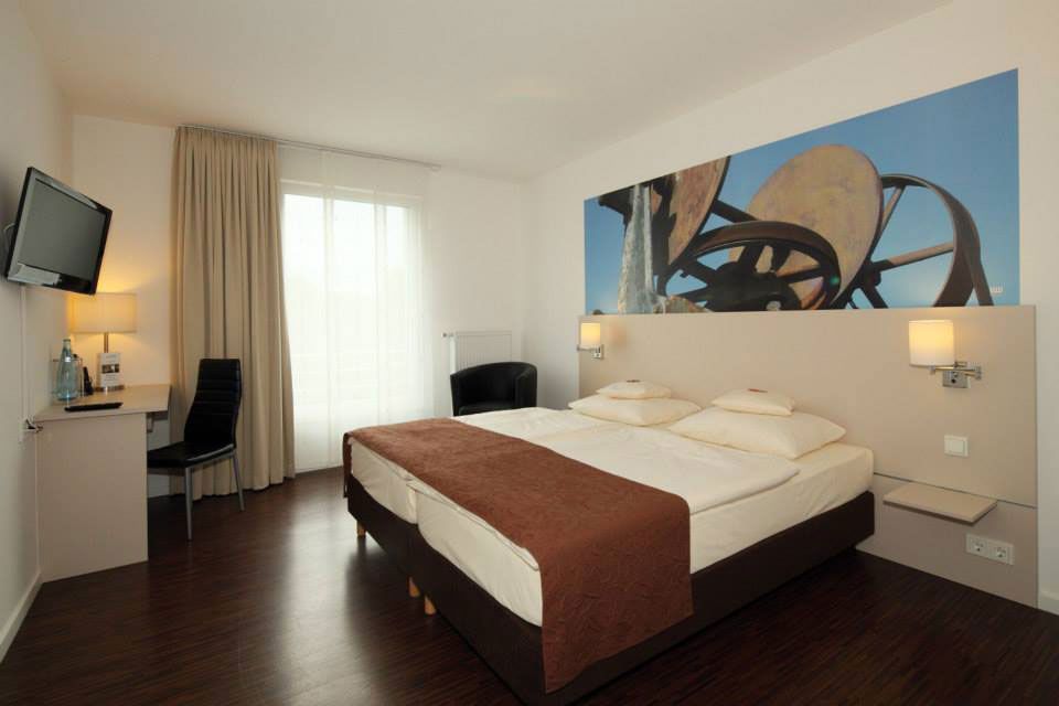 Ein geräumiges Hotelzimmer mit einem großen Bett und einem Flachbildfernseher für den Komfort und die Unterhaltung der Gäste.